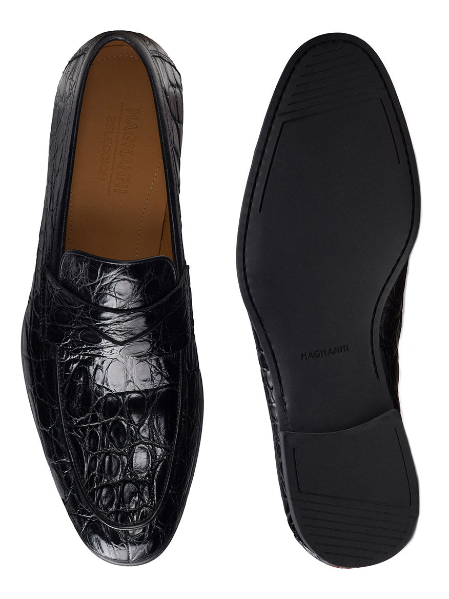 A pair of Magnanni Vicente Croc in Black loafers, featuring an elegant black leather with a distinct crocodile pattern. One shoe is displayed from the top and the other from the bottom, exuding a distinguished penny loafer style. The brand name "Magnanni" is prominently visible on both the insole and the sole, exemplifying their Línea Flex craftsmanship.