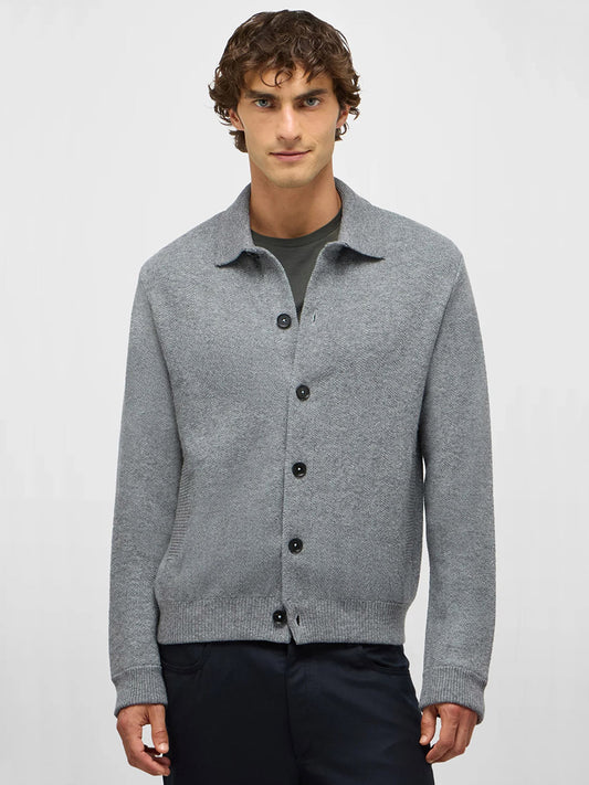 A man with short curly hair wears the Maurizio Baldassari Pique Knit Cashmere Blend Blouson in Light Grey over a dark shirt and pants, standing against a plain light background.