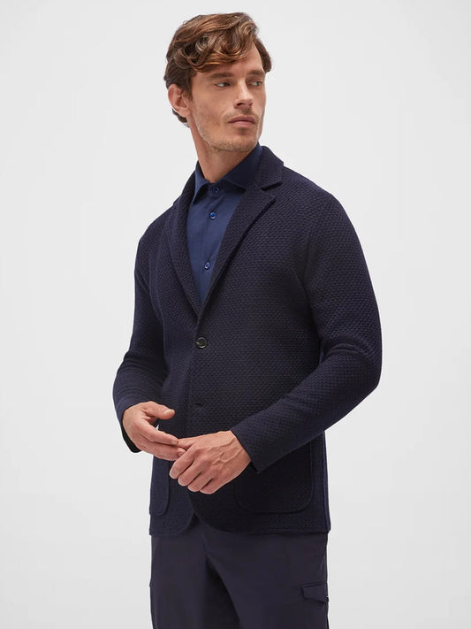 A man with short hair wearing a Maurizio Baldassari San Marco Wool Swacket in Deep Cobalt made in Italy over a dark shirt stands against a plain, light-colored background, looking slightly to the side.