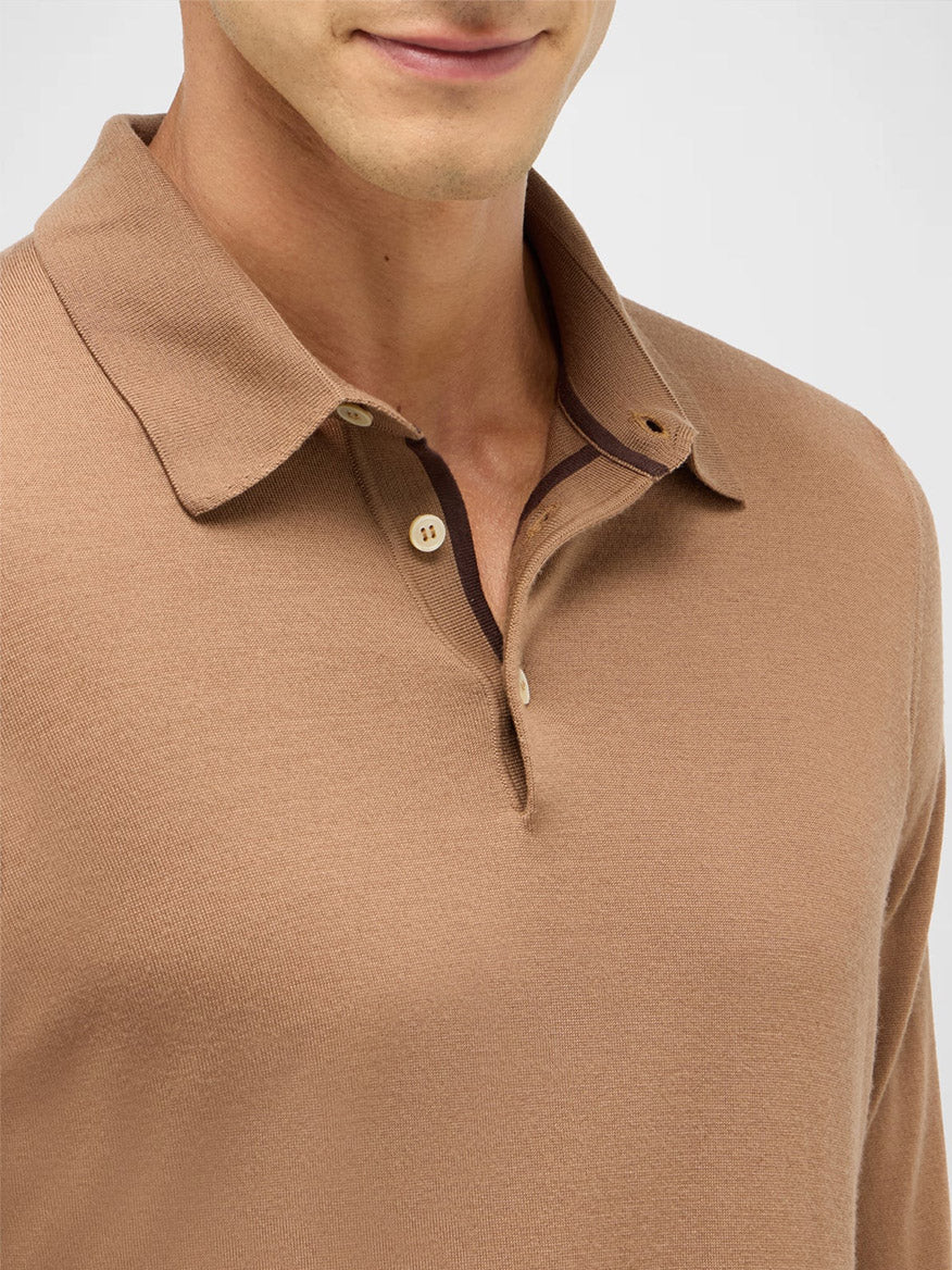 A person wears the Maurizio Baldassari 3-Button Long Sleeve Extrafine Wool Polo in Camel, made in Italy, shown from shoulders to mouth.