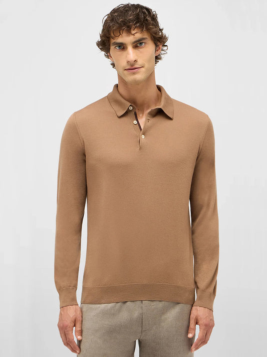 A man faces forward against a plain light background, wearing the Maurizio Baldassari 3-Button Long Sleeve Extrafine Wool Polo in Camel and beige pants.
