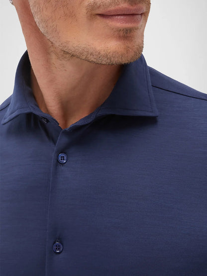 A close-up of a man wearing the Maurizio Baldassari Santini Techmerino Wool Shirt in Blue, showing his jawline, part of his mouth, and neck.