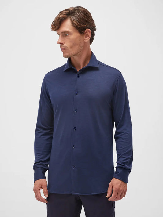 A man wearing the Maurizio Baldassari Santini Techmerino Wool Shirt in blue, with long sleeves, stands turned slightly to the side against a plain white background.
