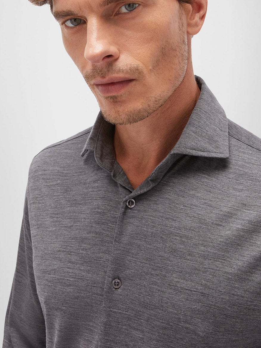 Close-up of a man wearing a dark grey Maurizio Baldassari Santini Techmerino Wool shirt, focusing on the collar and top buttons, with a serious expression.