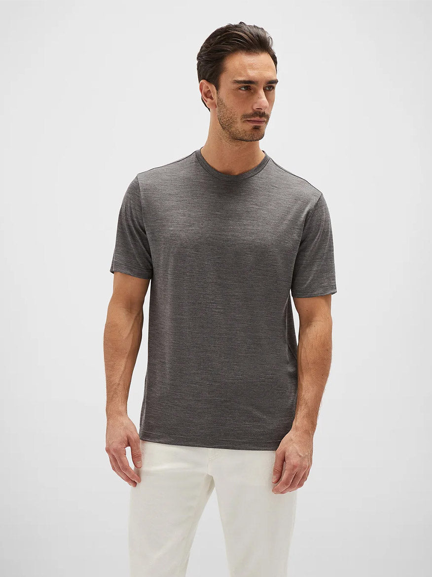 Man wearing a gray short-sleeve Maurizio Baldassari Linate Techmerino Short Sleeve T-Shirt in Medium Heather Grey and white pants standing against a plain white background.