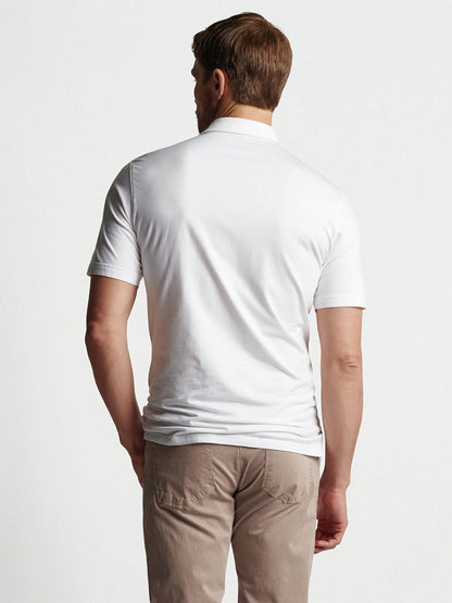 A man seen from behind, wearing a Peter Millar Excursionist Flex Short-Sleeve Polo in White and khaki pants designed for four-way stretch mobility.