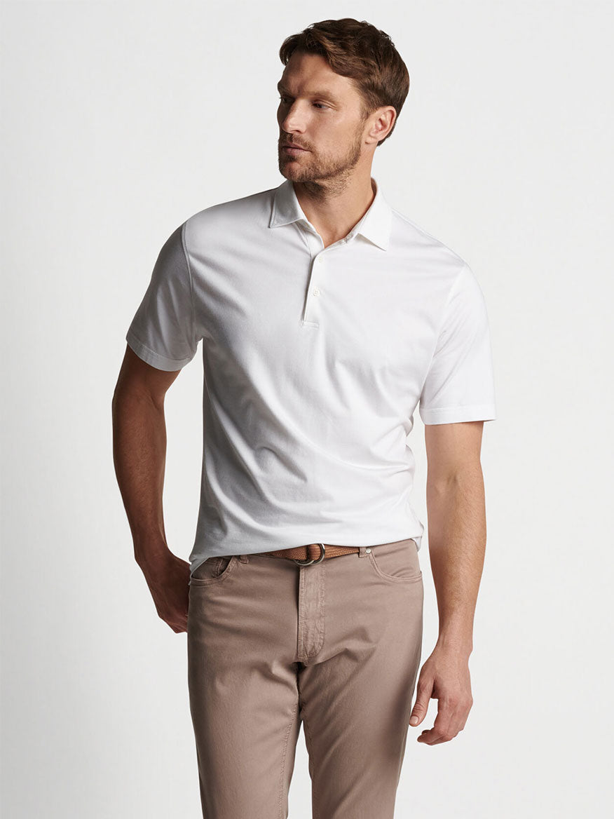 Man posing in a tailored fit Peter Millar Excursionist Flex Short-Sleeve Polo in White and beige trousers.
