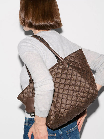 A woman with straight brown hair wears a light gray sweater and blue jeans, carrying the MZ Wallace Small Daily Tote in Walnut Oxford with Italian leather handles.