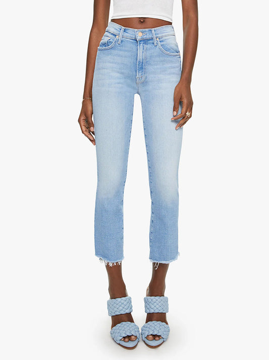 Woman wearing Mother Denim The Insider Crop Step Fray in Limited Edition ankle jeans with frayed hems and blue quilted sandals, standing against a plain white background.