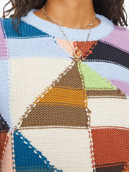 Close-up of a woman wearing a Mother Denim The Skipper Bell Jumper in Deja Vu and a layered necklace with a pearl pendant.