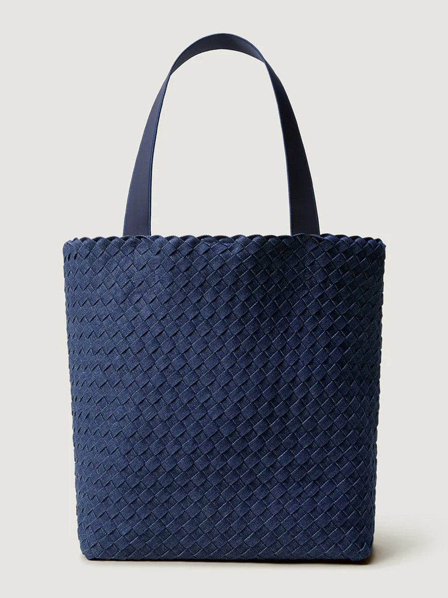 The Naghedi Como Shopper Tote in Denim is a navy blue handwoven bag featuring a woven texture and two flat handles, displayed against a plain light background.