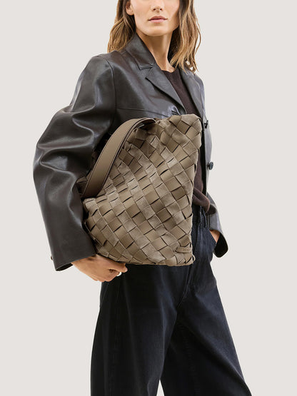 A person carrying a large, taupe-colored Naghedi Como Shopper Tote Suede & Neoprene in Bluff under their arm.