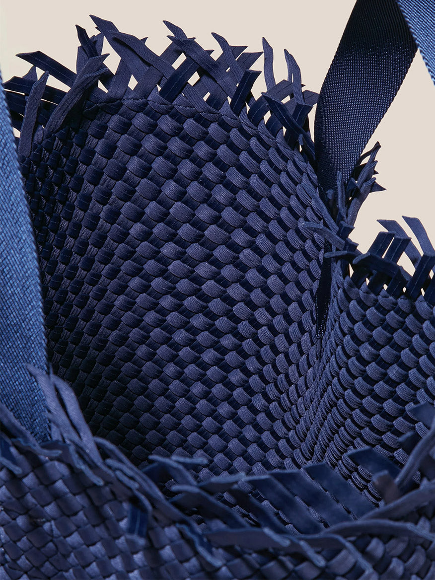 Close-up of a textured Naghedi Havana Large Travel Tote in Solid Ink Blue Fringe neoprene fabric with frayed edges.