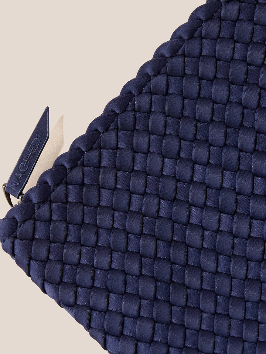 Close-up of a Naghedi Havana Large Travel Tote in Solid Ink Blue Fringe with a branded tag.