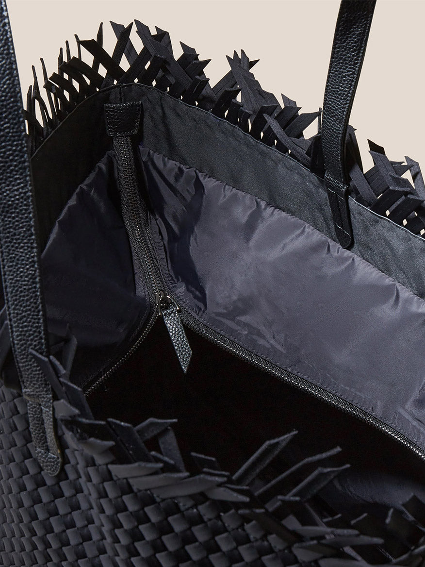 Close-up of an open Naghedi Havana Large Travel Tote in Solid Onyx Fringe with distinctive handwoven neoprene texture on the exterior and sleek black lining.