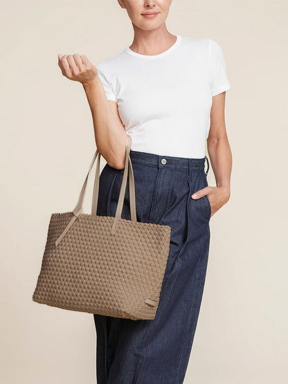 Person wearing a white t-shirt and blue pants, carrying the chic Naghedi Jetsetter Small Tote in Solid Cashmere on their shoulder.