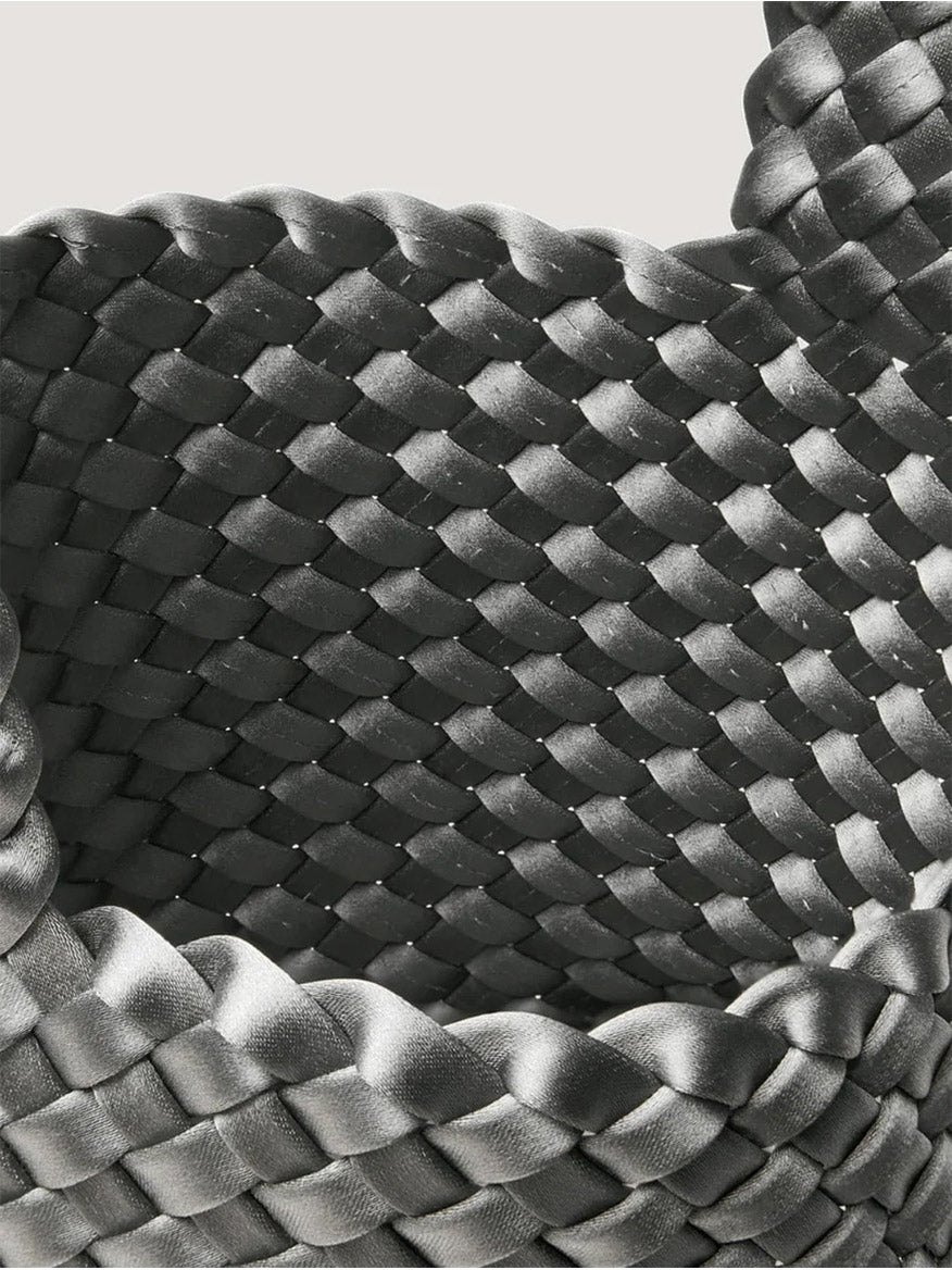 Close-up of a charcoal gray Naghedi Kyoto Clutch Satin in Graphite, featuring a woven design with a glossy finish.