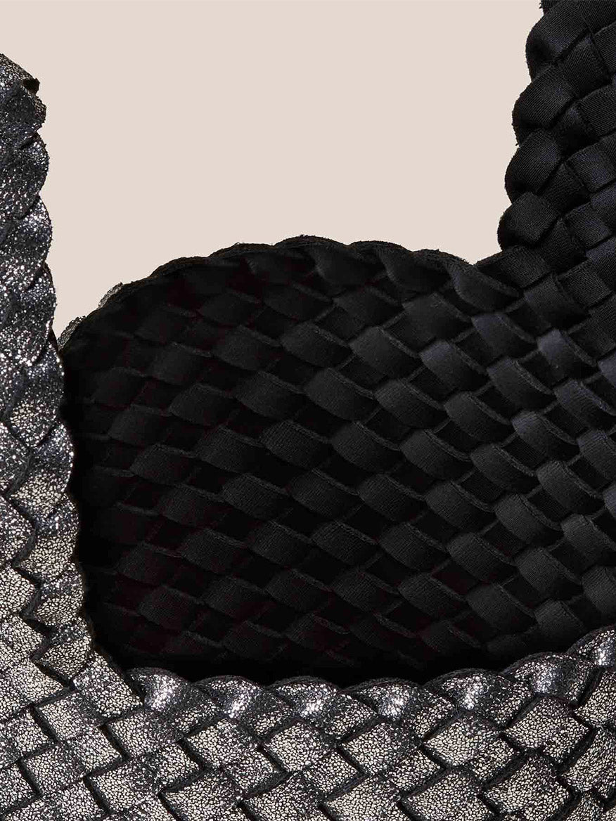 Close-up of handwoven neoprene texture with black and silver braided patterns on a neutral background, perfect for accentuating the Naghedi Kyoto Clutch in Metallic Titanium for elegant evening outfits.