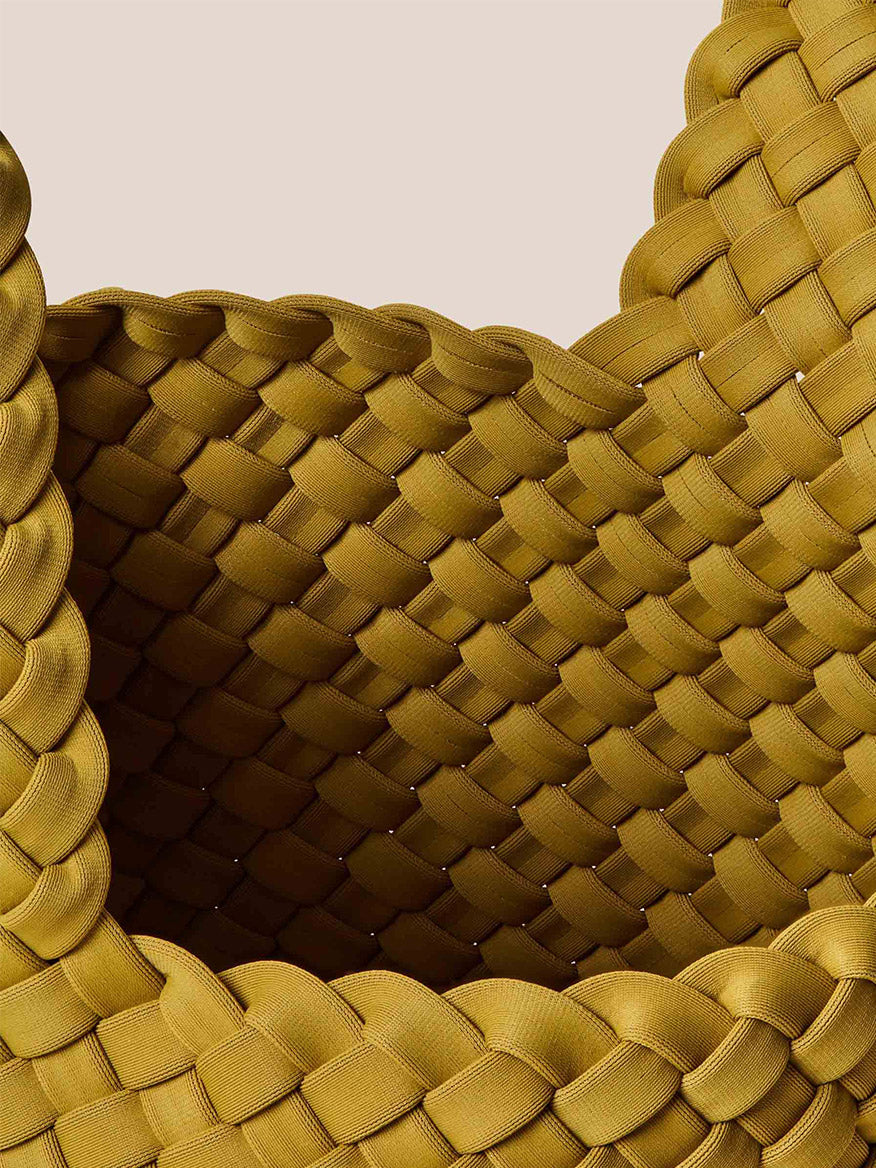 Close-up of the Naghedi Kyoto Clutch in Solid Chartreuse, exquisitely handwoven in mustard-colored neoprene, showcasing its intricate overlapping braided patterns and thick edges against a beige background. Perfect for elevating evening outfits with an artistic flair.