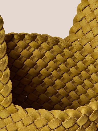 Close-up of the Naghedi Kyoto Clutch in Solid Chartreuse, exquisitely handwoven in mustard-colored neoprene, showcasing its intricate overlapping braided patterns and thick edges against a beige background. Perfect for elevating evening outfits with an artistic flair.