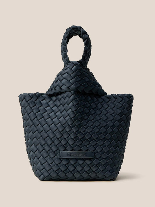 The Naghedi Kyoto Clutch in Solid Murano, crafted from handwoven neoprene and featuring a twisted handle, stands elegantly against a plain background. Its unique flair and sophisticated design make it the perfect complement for evening outfits.