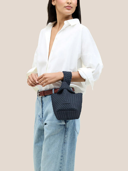 A person in a white shirt, jeans, and a brown belt holds the elegant Naghedi Kyoto Clutch in Solid Murano, ideal for evening outfits.