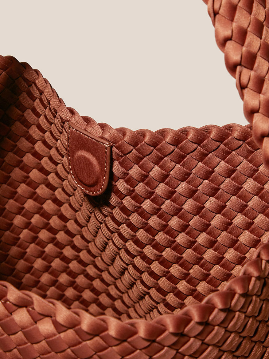 Close-up of a textured brown Naghedi Nomad Hobo in Solid Adobe handwoven hobo bag with a leather snap closure.
