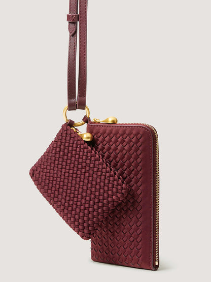Deep red woven Naghedi Orly Phone Case in Bordeaux with a matching small pouch suspended from an adjustable leather strap.