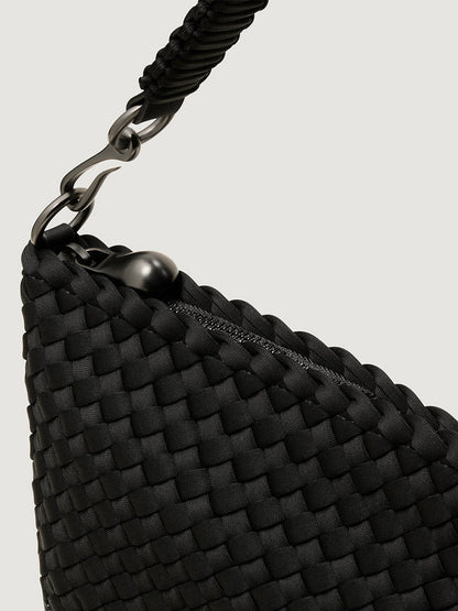Close-up of the Naghedi Porto Medium Half-Moon Bag in Onyx, featuring handwoven black material, a zippered opening, and a braided strap secured by a metal clasp.