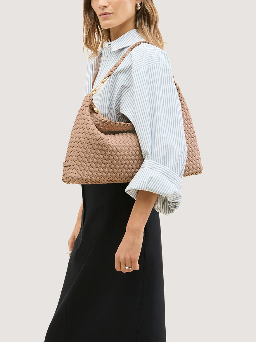 A tan, half-moon shaped woven Naghedi Porto Medium Half-Moon Bag in Seychelles with a matching shoulder strap.