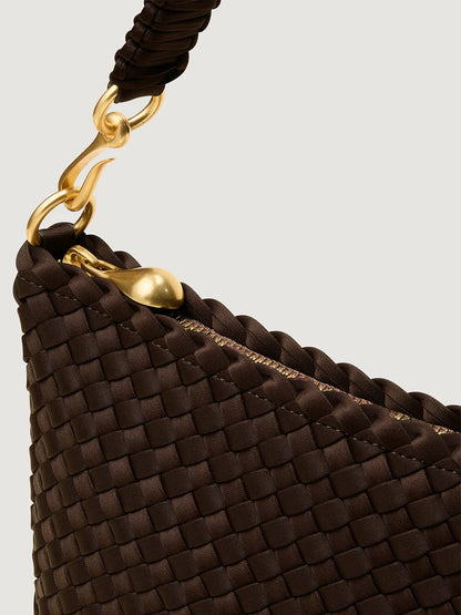 Close-up of the Naghedi Porto Small Half-Moon Bag in Chocolate, a dark brown handwoven neoprene accessory with a gold zipper, braided handle, and gold hardware, set against a neutral background.