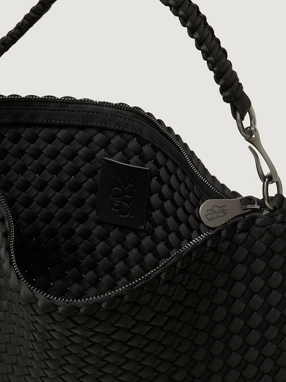 Close-up of the open top of the Naghedi Porto Small Half-Moon Bag in Onyx, showing its black handwoven neoprene exterior, interior lining, black brand tag, and silver zipper.