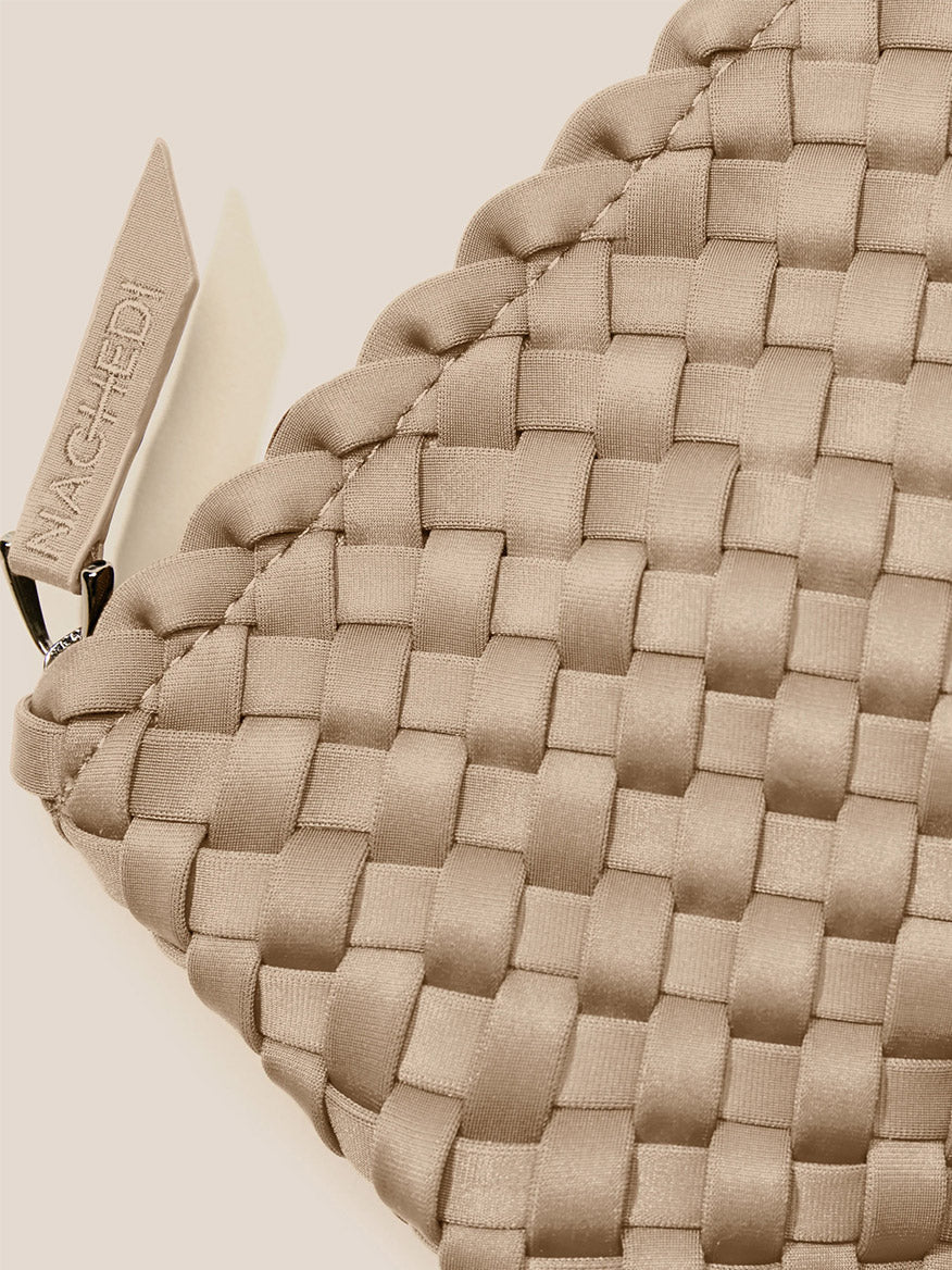 Close-up of a beige handwoven neoprene Naghedi Portofino Cosmetic Clutch in Solid Cashmere with a visible brand tag.