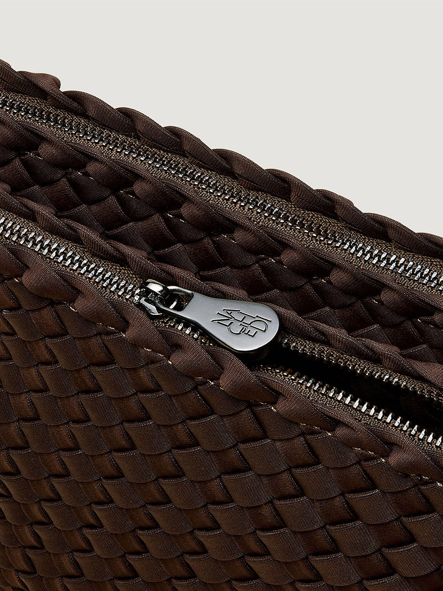 Close-up of a dark brown woven neoprene Naghedi Soho Envelope Crossbody in Chocolate with a zippered closure and a branded silver zipper pull.