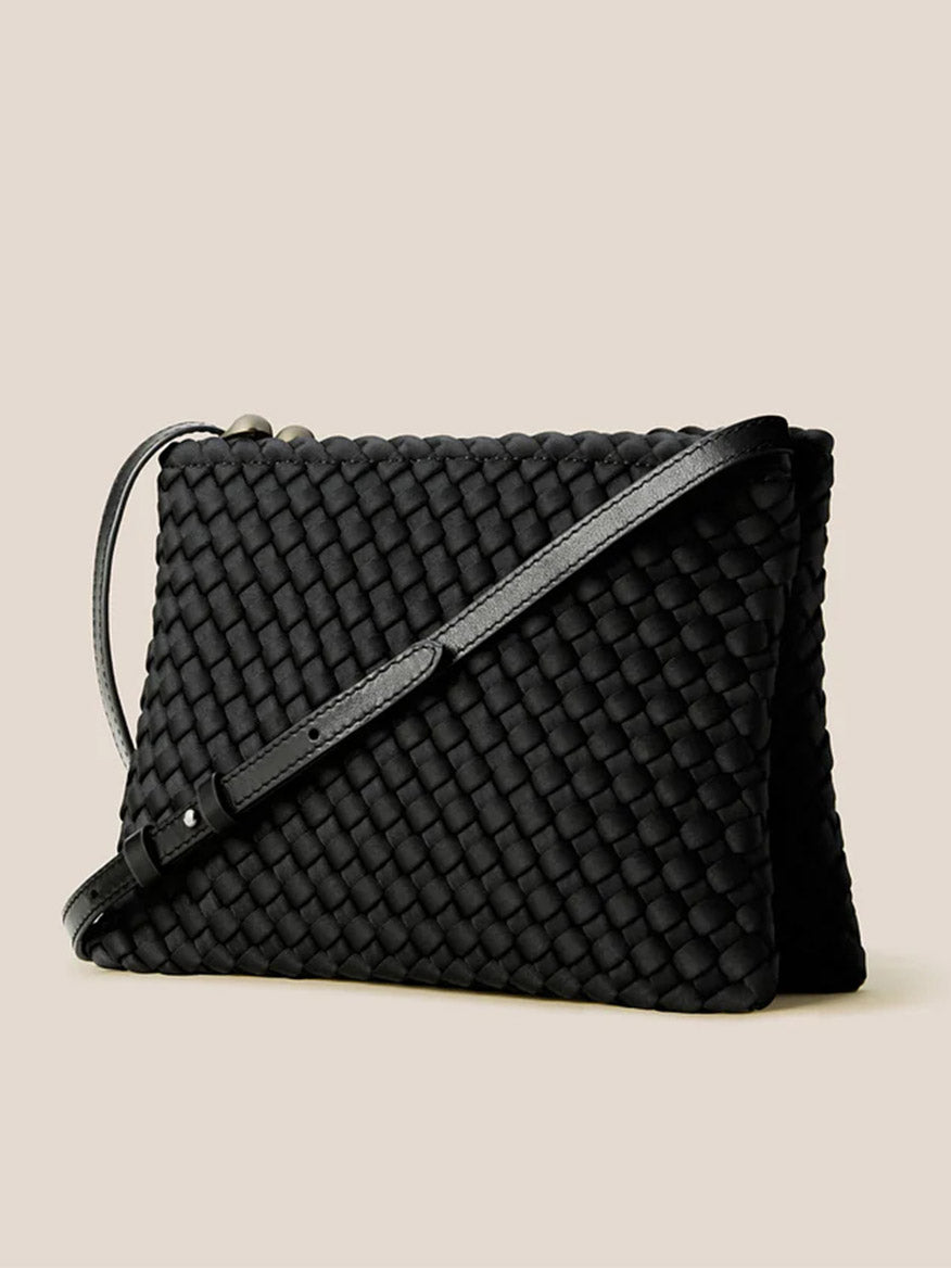 The Naghedi Soho Envelope Crossbody in Onyx features woven leather and a long, adjustable strap, shown against a plain beige background.