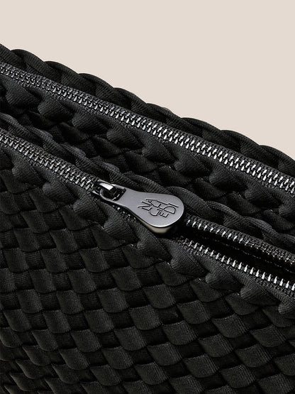 Close-up of the Naghedi Soho Envelope Crossbody in Onyx, featuring black woven neoprene, a silver zipper with branded pull tab, and an adjustable crossbody strap.