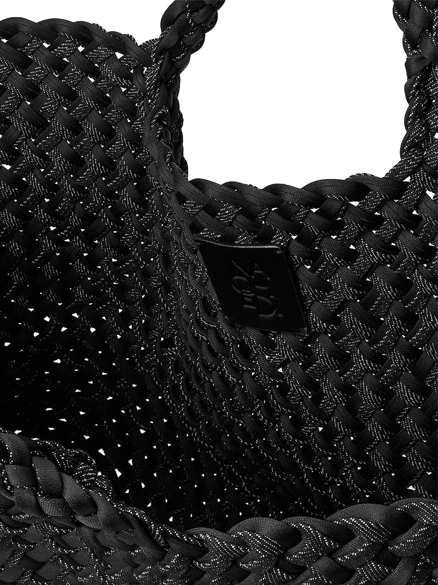 Close-up of a black Naghedi St. Barths Medium Double Weave Tote in Jet, showing its handwoven neoprene texture and a small square brand tag on the interior.
