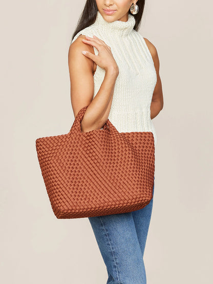 A woman in a white turtleneck and jeans holds a Naghedi St. Barths Medium Tote in Solid Adobe.