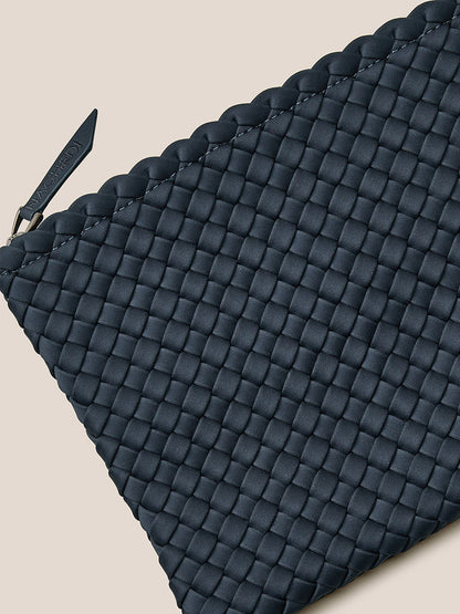 Close-up of a dark woven clutch featuring a zipper and a scalloped edge, crafted from handwoven neoprene. Ideal as an everyday bag, it embodies the stylish design of the Naghedi St. Barths Medium Tote in Solid Murano.