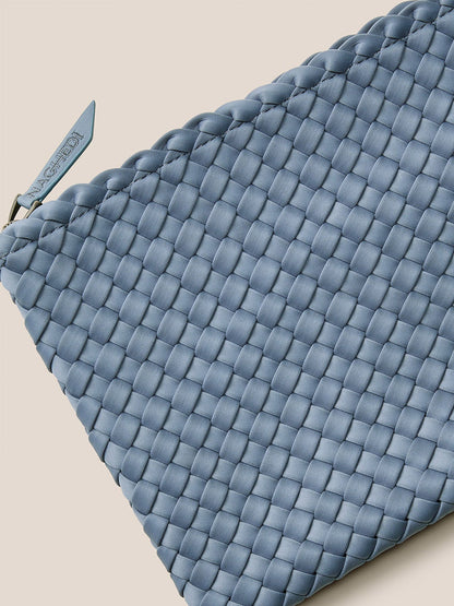 A close-up of a blue woven leather clutch with zipper closure, reflecting the refined craftsmanship of a Naghedi St. Barths Medium Tote in Solid Nova.