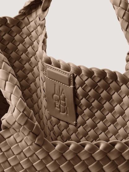 Close-up of a handwoven taupe Naghedi St. Barths Medium Tote in Cashmere, featuring a branded leather patch on the interior.