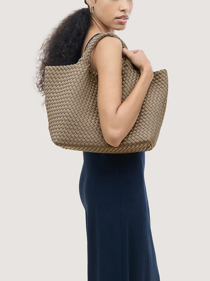 A woman carrying a handwoven taupe Naghedi St. Barths Medium Tote in Cashmere over her shoulder.