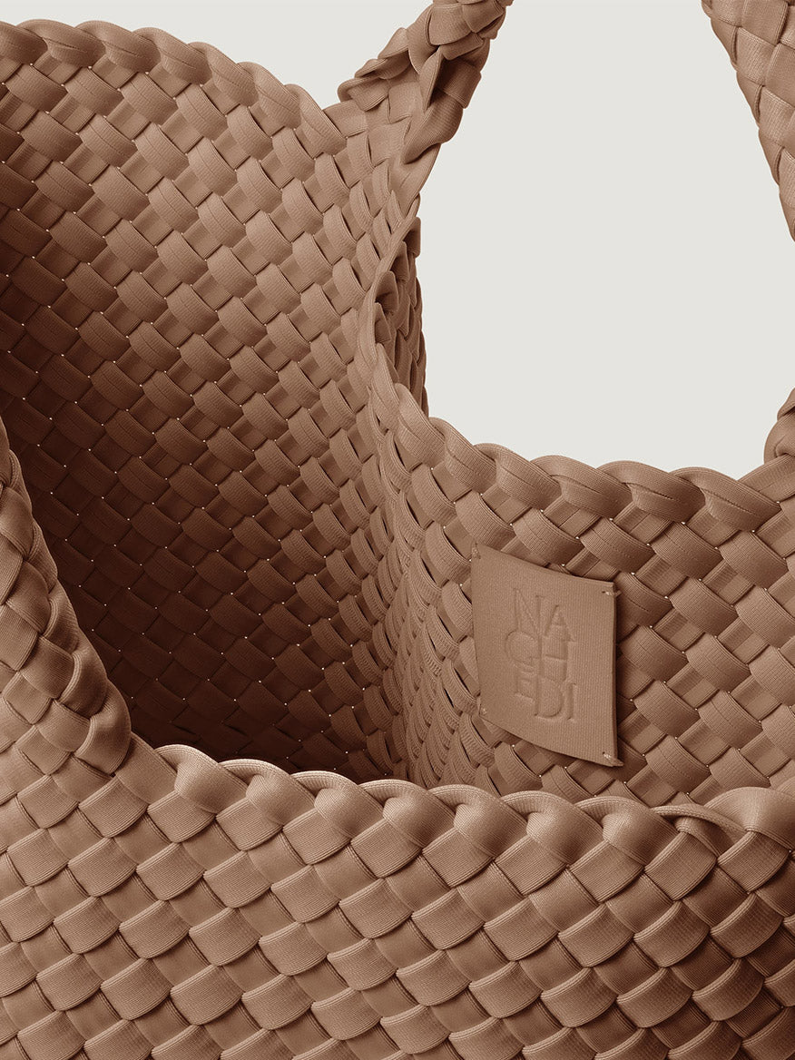 Close-up of a medium-brown Naghedi St. Barths Medium Tote in Seychelles, featuring a matching brand patch on the interior.