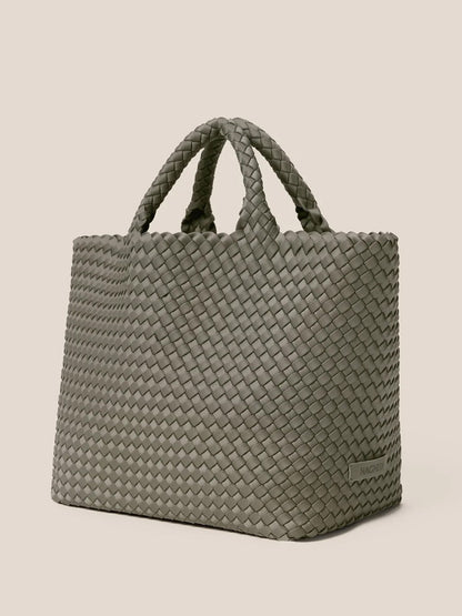 The Naghedi St. Barths Medium Tote in Solid Laurel is a versatile everyday bag showcasing a green, handwoven neoprene design with two sturdy handles against a beige background.