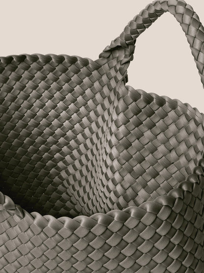 A close-up shot of the Naghedi St. Barths Medium Tote in Solid Laurel, showcasing its textured handwoven neoprene design and handle against a plain background.