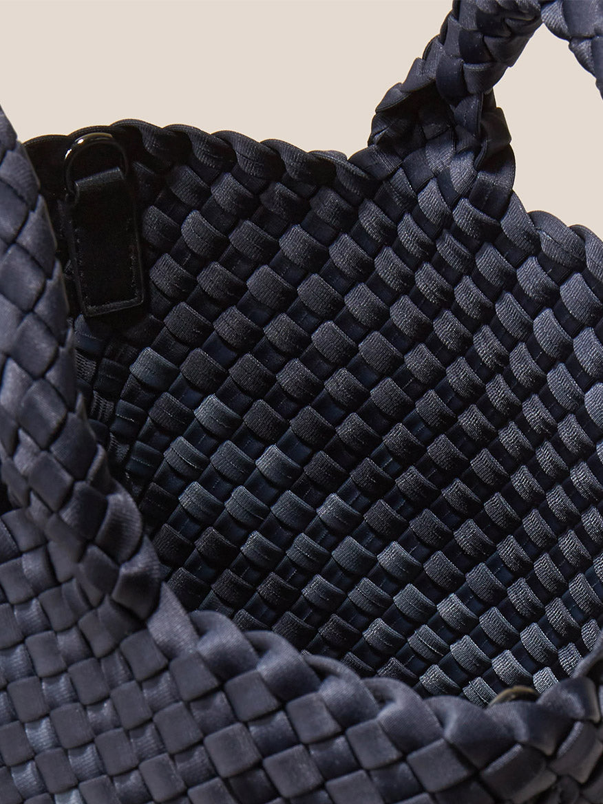 Close-up view of a Naghedi St. Barths Small Tote in Graphic Ombre Basalt with intricate texture and a handle attached by a black clasp.