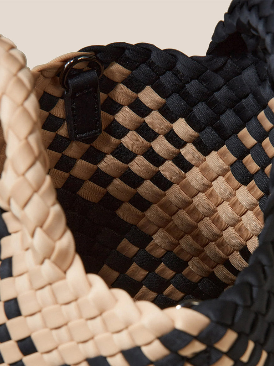 Close-up view of a Naghedi St. Barths Petit Tote in Plaid Cabana featuring an intricate pattern of black and tan strips with a focus on the textured details.