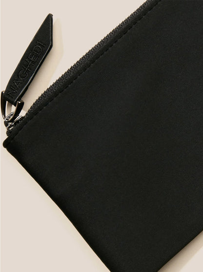 Close-up of a black fabric pouch, showcasing a visible zipper and a leather pull tag embossed with "NAGHEDI." It captures the sophisticated charm of the Naghedi St. Barths Petit Tote in Watercolor Nimbus, enhanced by its handwoven neoprene detailing for added texture.