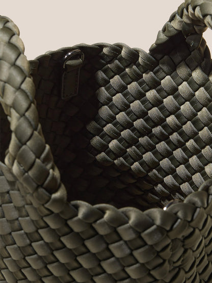 Close-up of an open, handwoven neoprene basket with thick, dark gray braids and handles. Reminiscent of the Naghedi St. Barths Petit Tote in Solid Olive, this piece blends traditional craftsmanship with modern materials.