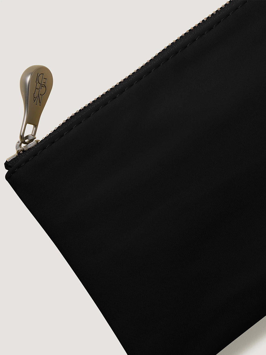 Black handwoven neoprene Naghedi St. Barths Petit Tote in Onyx with a zippered closure and a metallic logo pull.